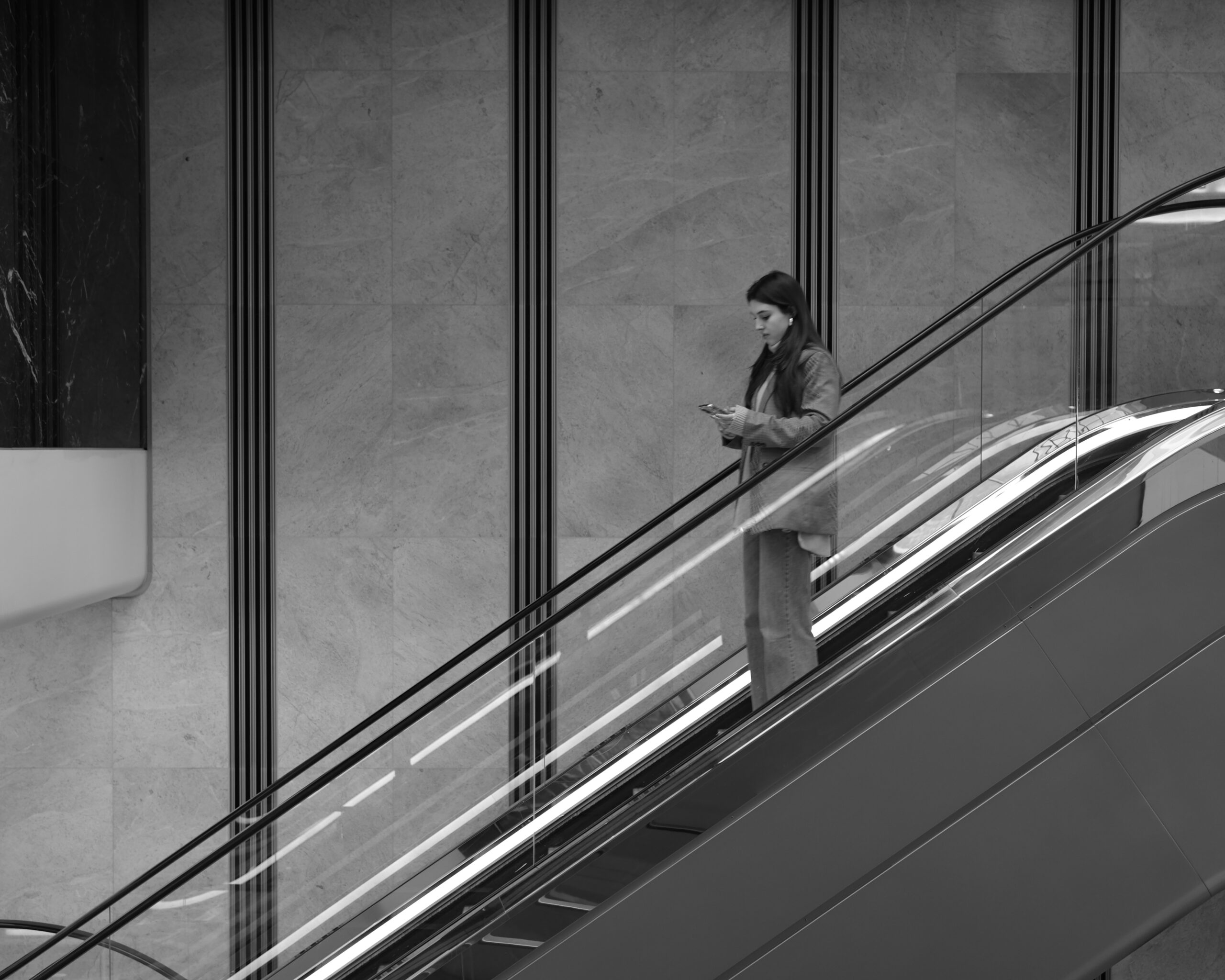 Klassmir Photography Girl in escalator looking at her phone in black and white